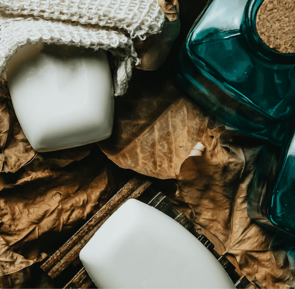 Two white mugs on a wooden surface with a green bottle and brown fabric in the background.